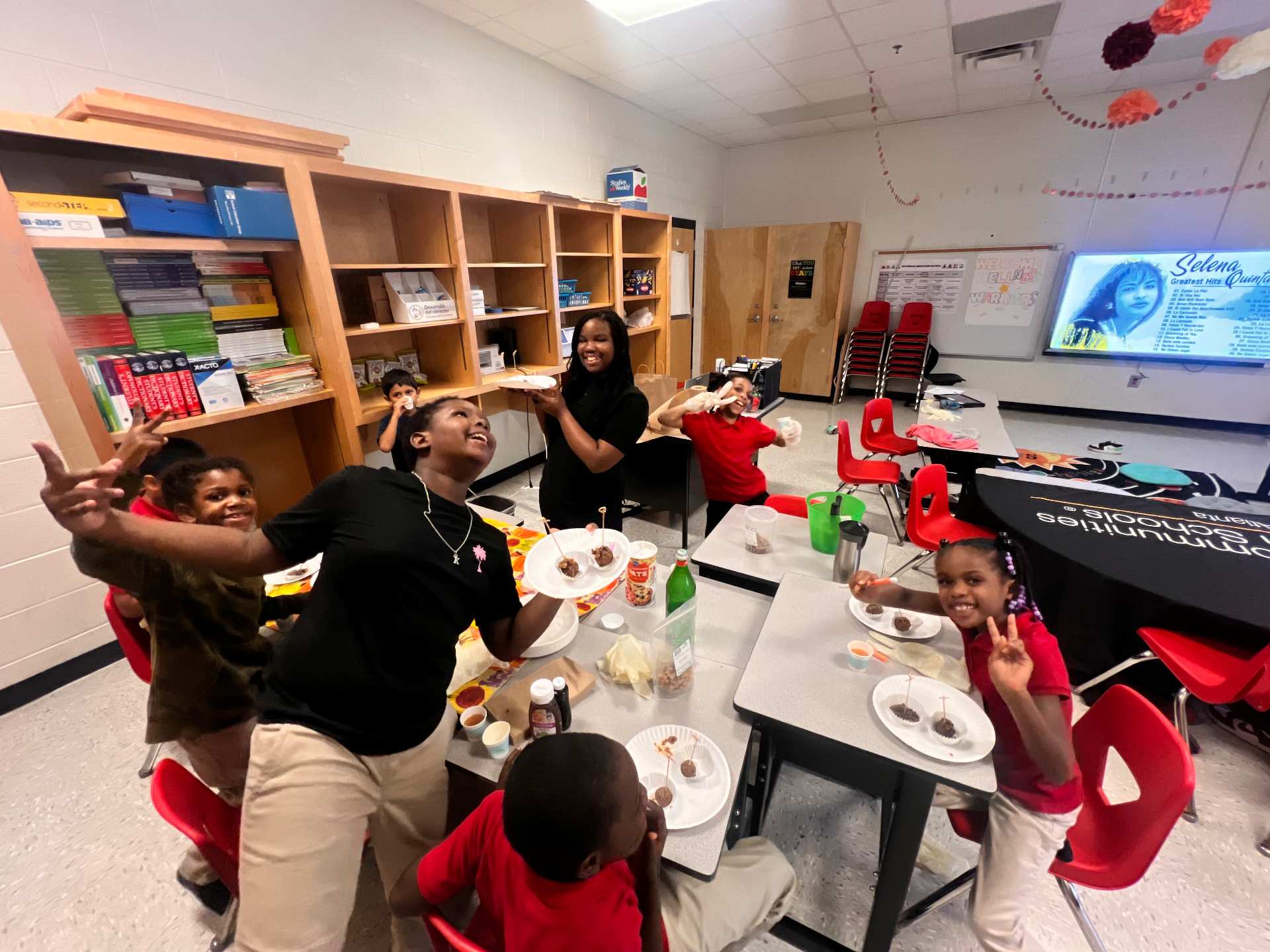 Children holding up plates they made around a classroom table