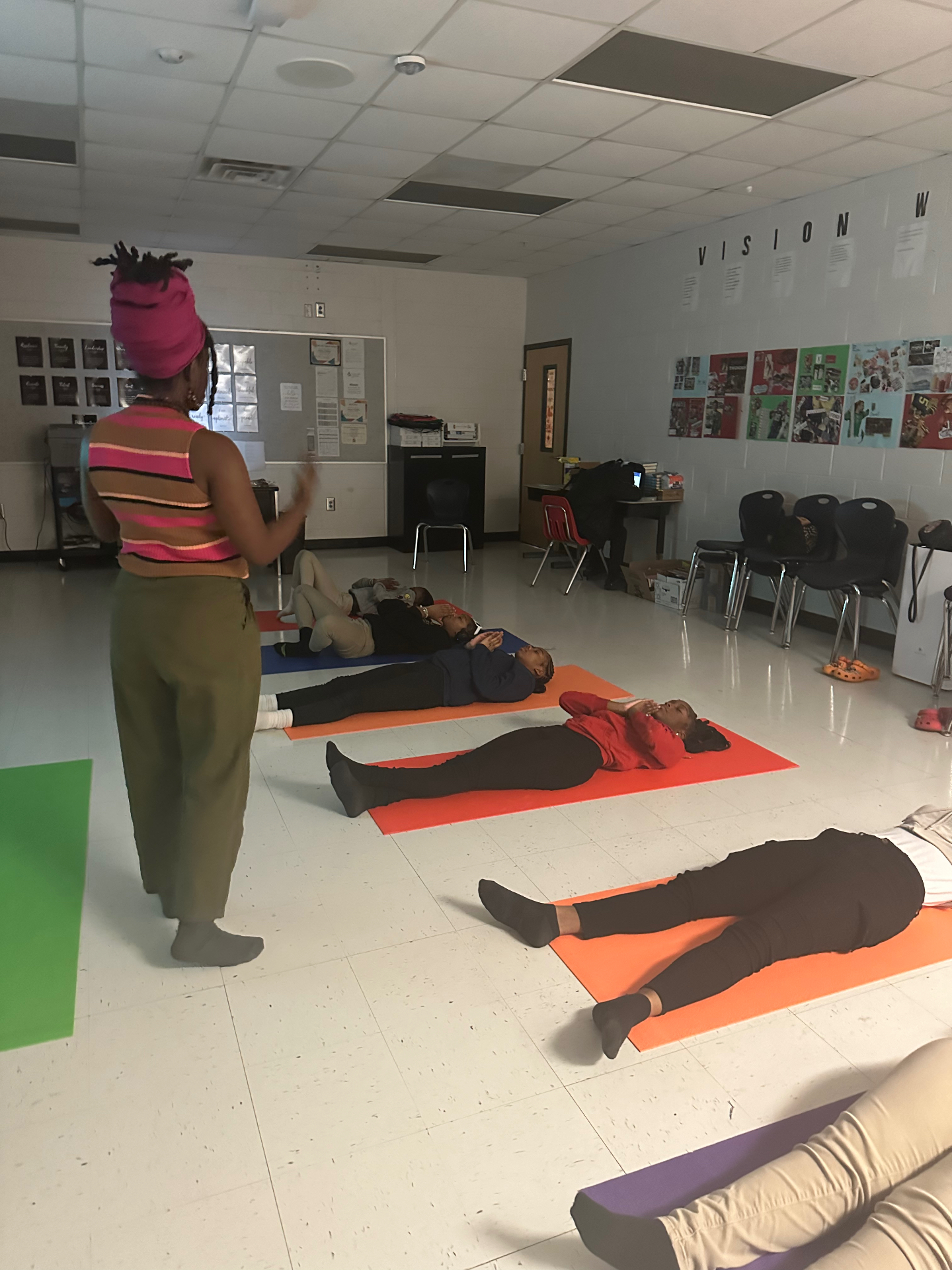 Facilitator moving quietly among students resting on mats during a wellness session