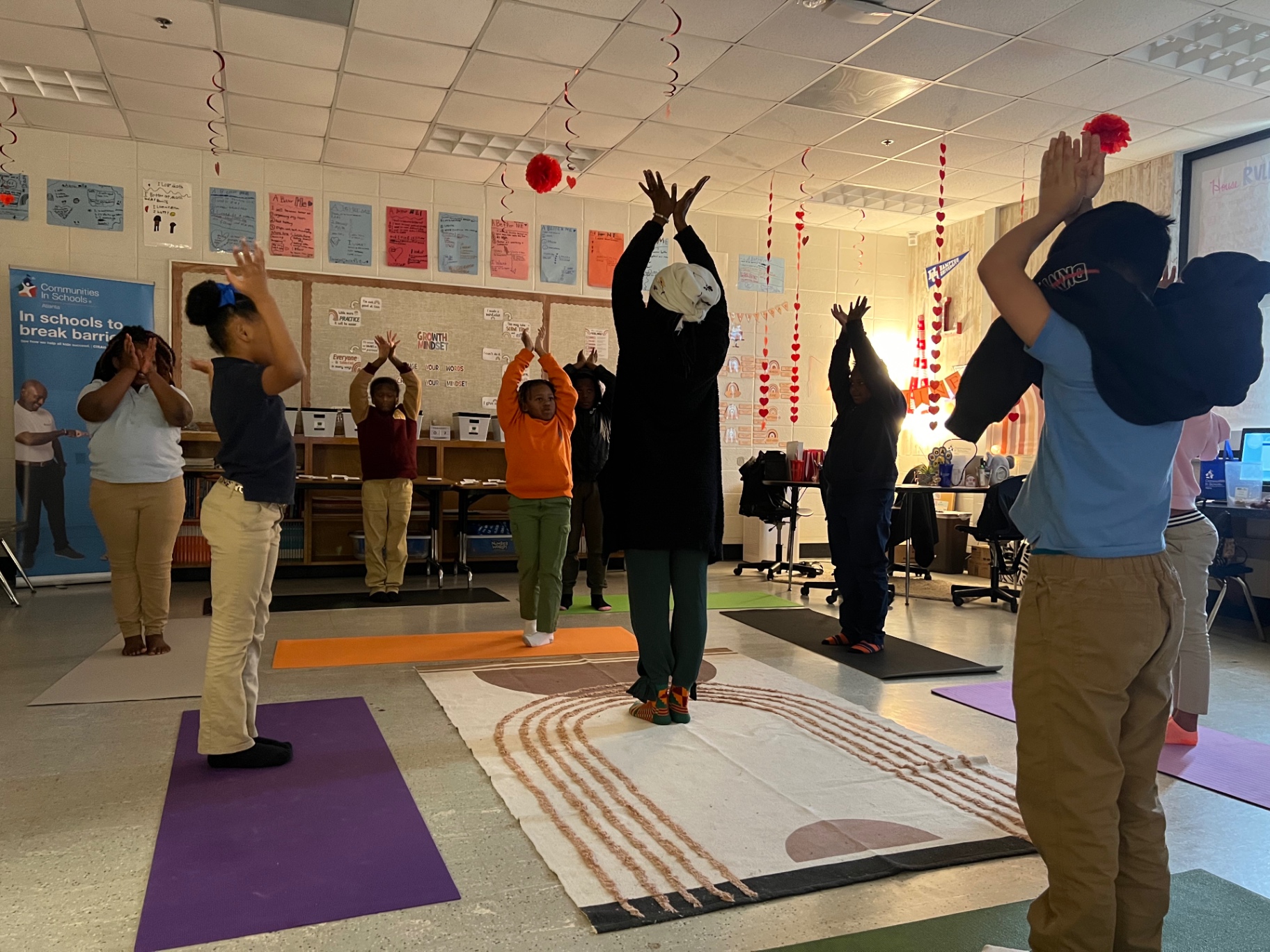 Children pressing palms overhead in unison as a facilitator leads from the center
